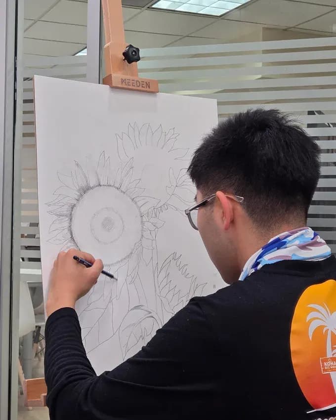Youngjun sketching a sunflower at an easel in a Seesaw art class.