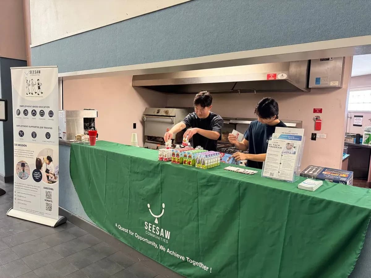 Two participants serving drinks at the green Seesaw coffee table indoors.